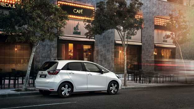 Honda Jazz Hybrid set bagfra uden for en café