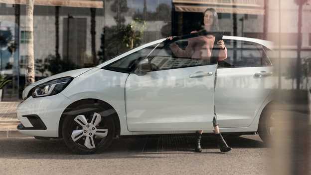 Honda Jazz set fra siden, parkeret med dame, der åbner døren