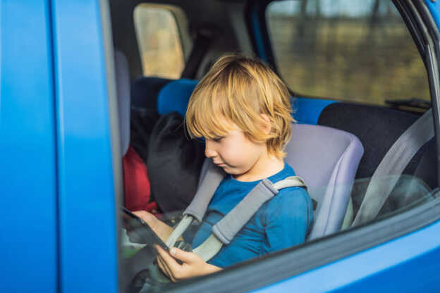 Dreng spiller på tablet på en biltur