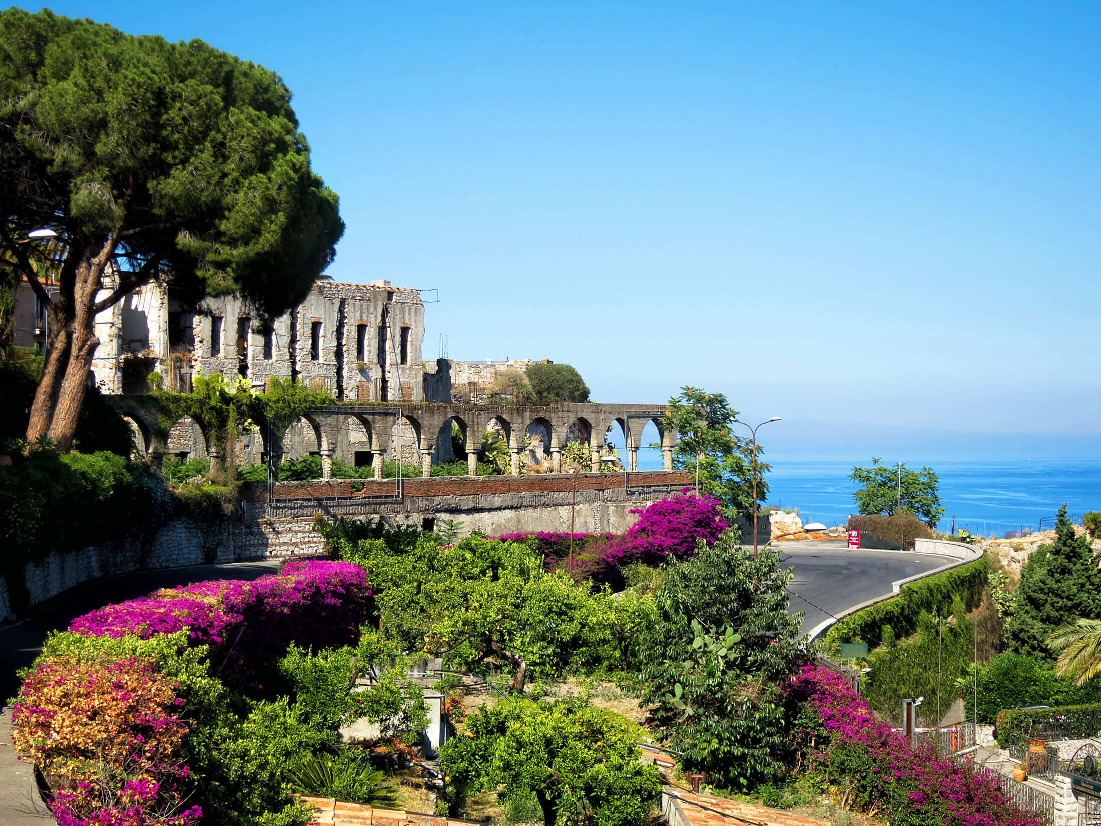 En farverig have i nærheden af en gammel bygning på Sicilien, Italien