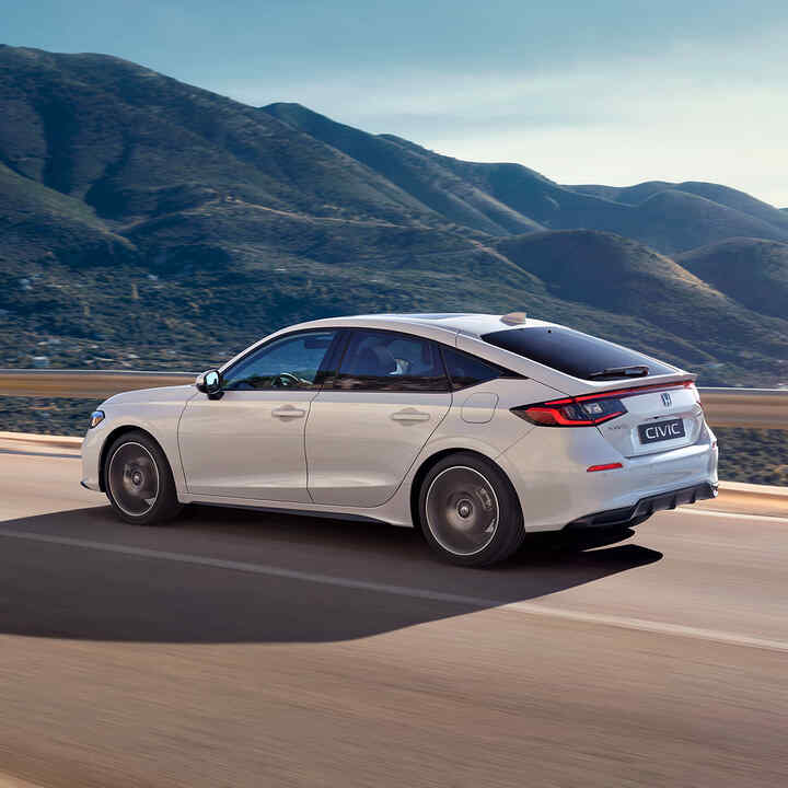 Honda Civic Hybrid i bevægelse på en motorvej i et naturskønt landskab.