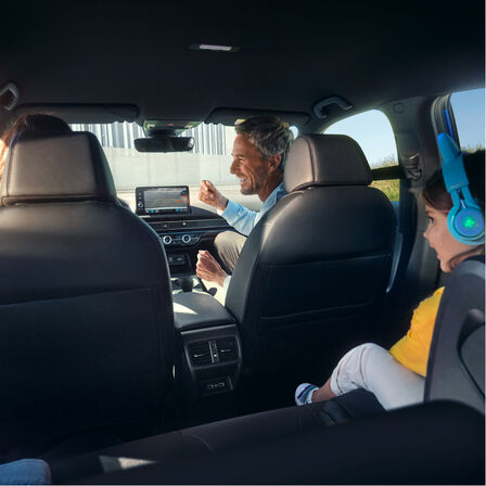 Udsigt fra bagsæderne af en familie, der sidder inde i bilen.