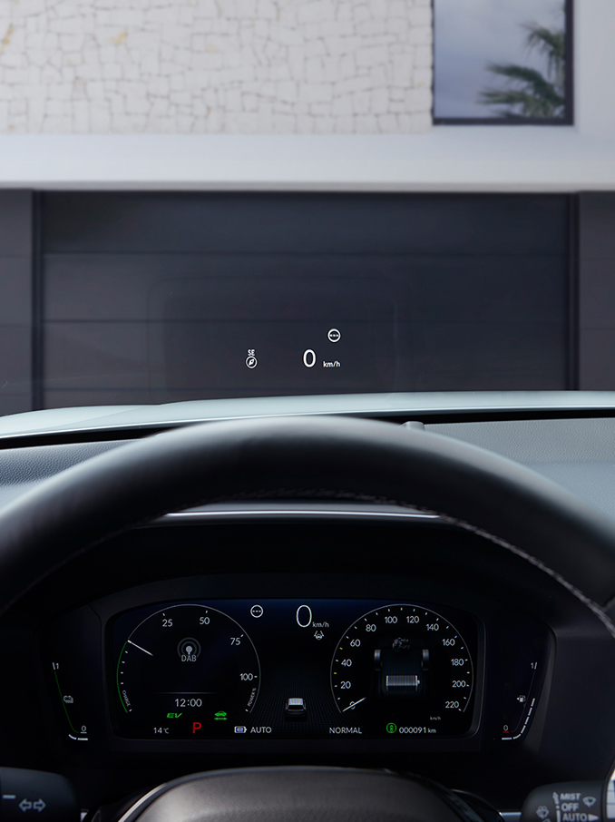 Fra førersædet ses et head-up-display (HUD), der projicerer "50 km/t" og et kompas på forruden over en grusvej.