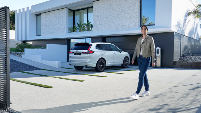 En hvid CR-V PHEV og en person, der går hen mod bilen