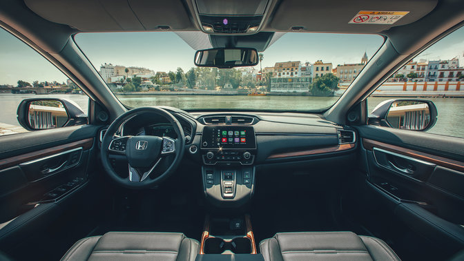 Nærbillede af Honda CR-V Hybrids instrumentbræt, set ud mod en gade.