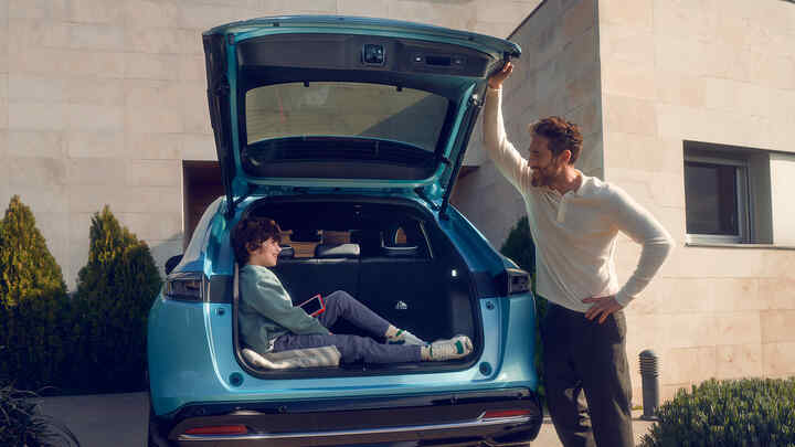 Far taler til et barn, der sidder i bagagerummet på Honda e:Ny1.