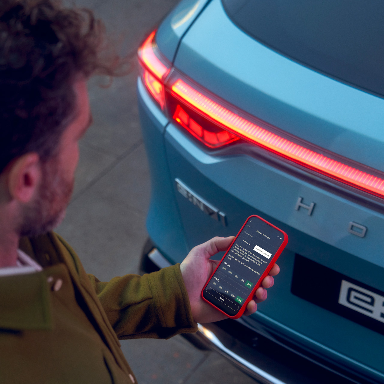 Mand, der ser på My Honda Plus-appen ved siden af Honda e:Ny1