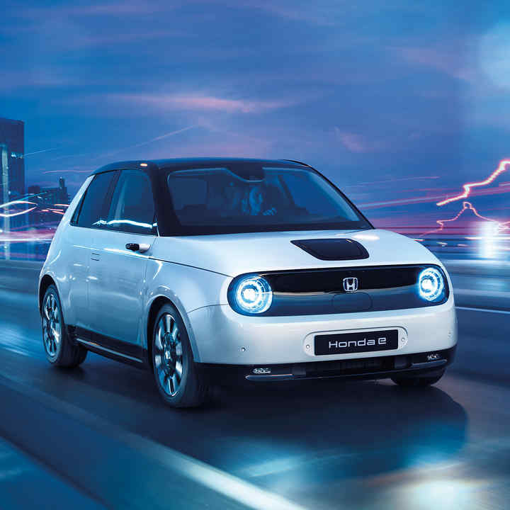 Honda e, set skråt forfra, på vej gennem elektrisk bymiljø.