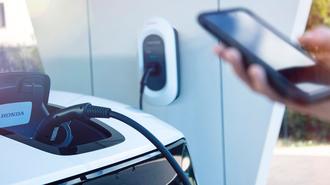 Model, der viser My Honda+ appen, der viser opdateringer om ladestatus.
