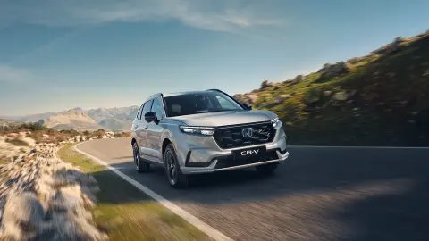 Hvid CR-V Plug-in Hybrid, der kører på vejen i et bjergområde.