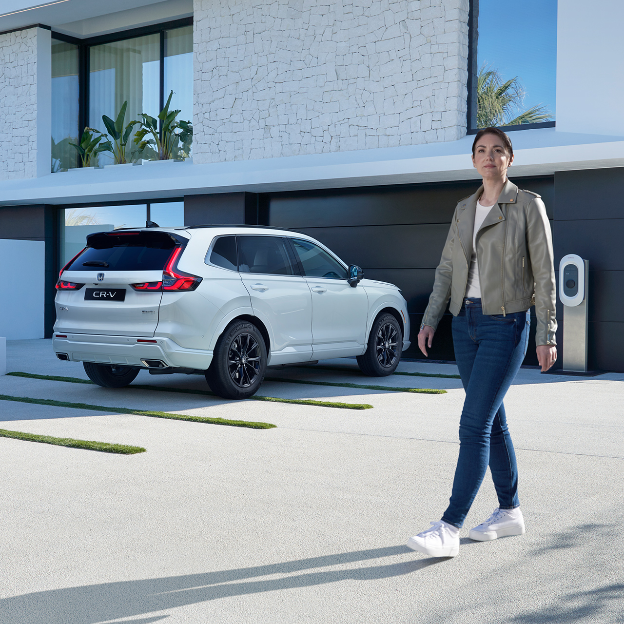 Model, der går i nærheden af hvid parkeret CR-V Plug-in Hybrid.
