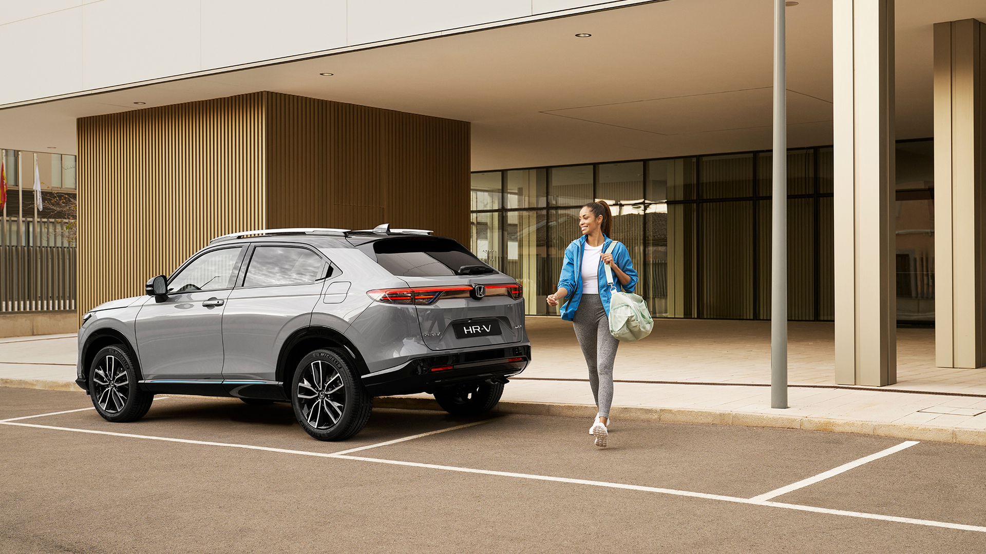 Kvinde går langs med en parkeret HR-V. 