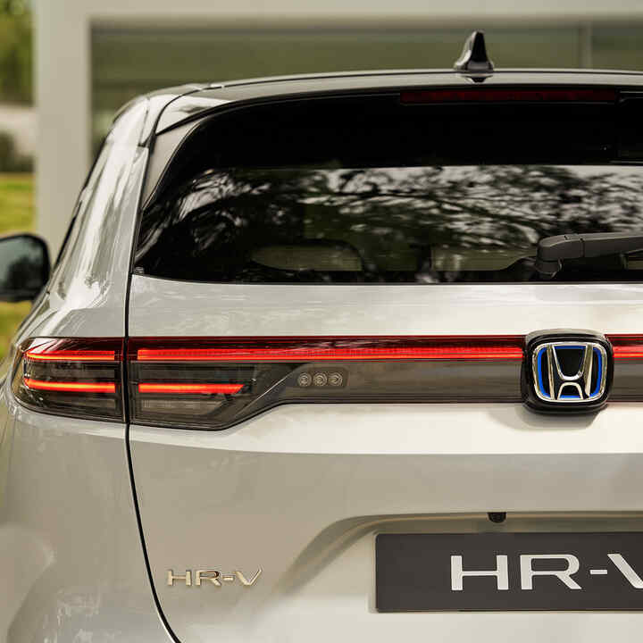 Par går ved siden af ​​HR-V, der er parkeret uden for en bygning. 
