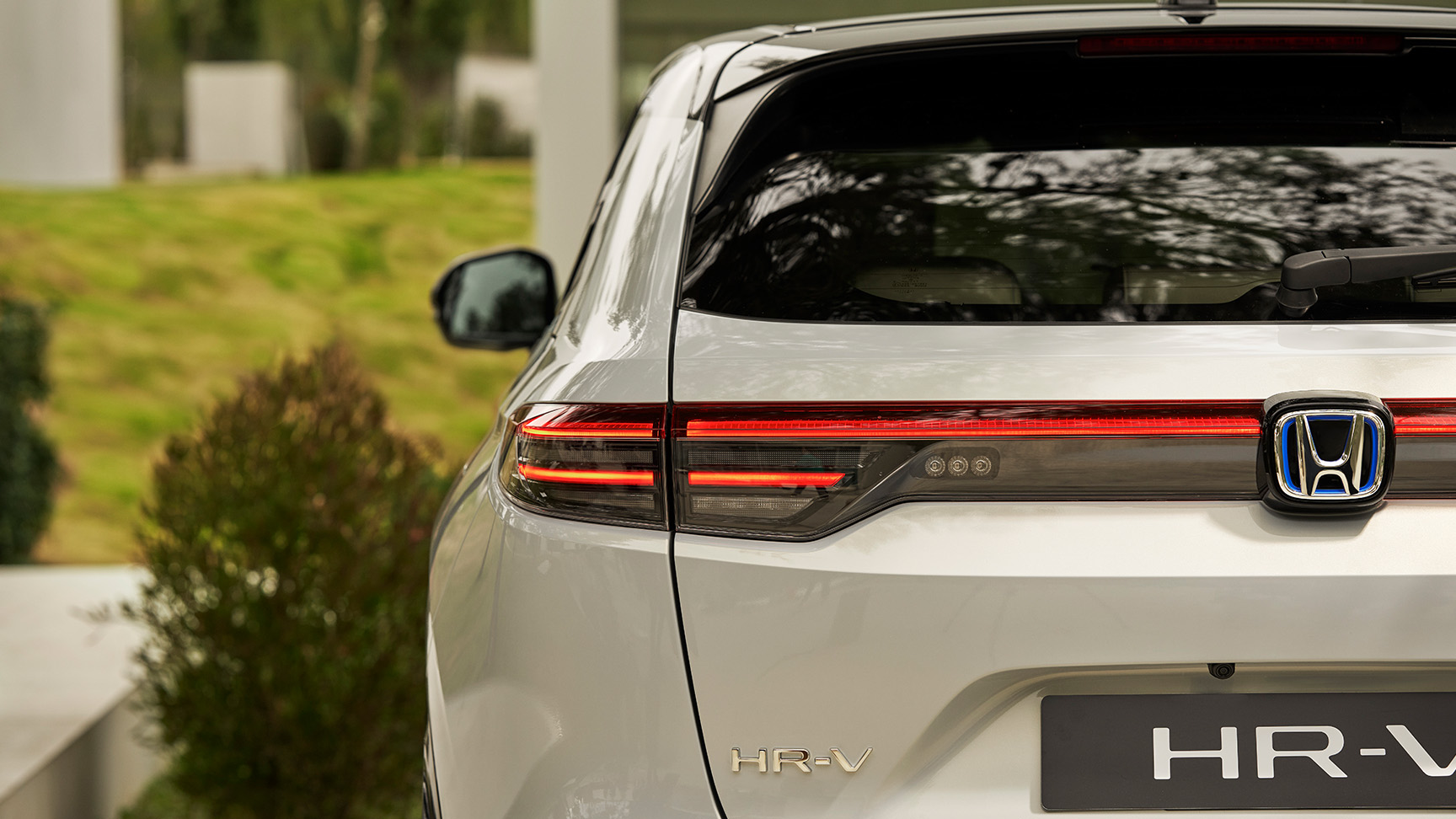 Par går ved siden af ​​HR-V, der er parkeret uden for en bygning. 