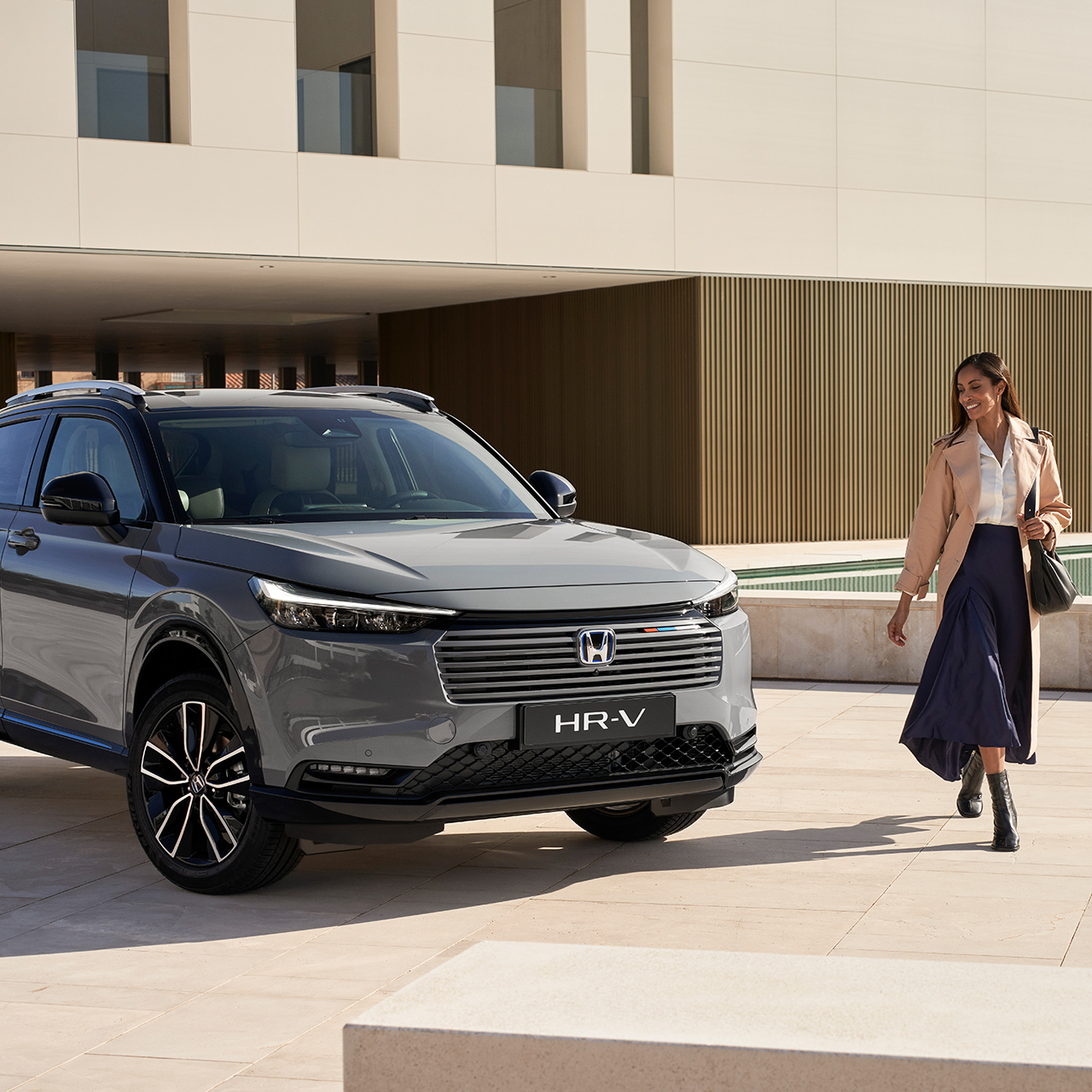 Par, der går ved siden af ​​HR-V parkeret uden for bygningens placering. 