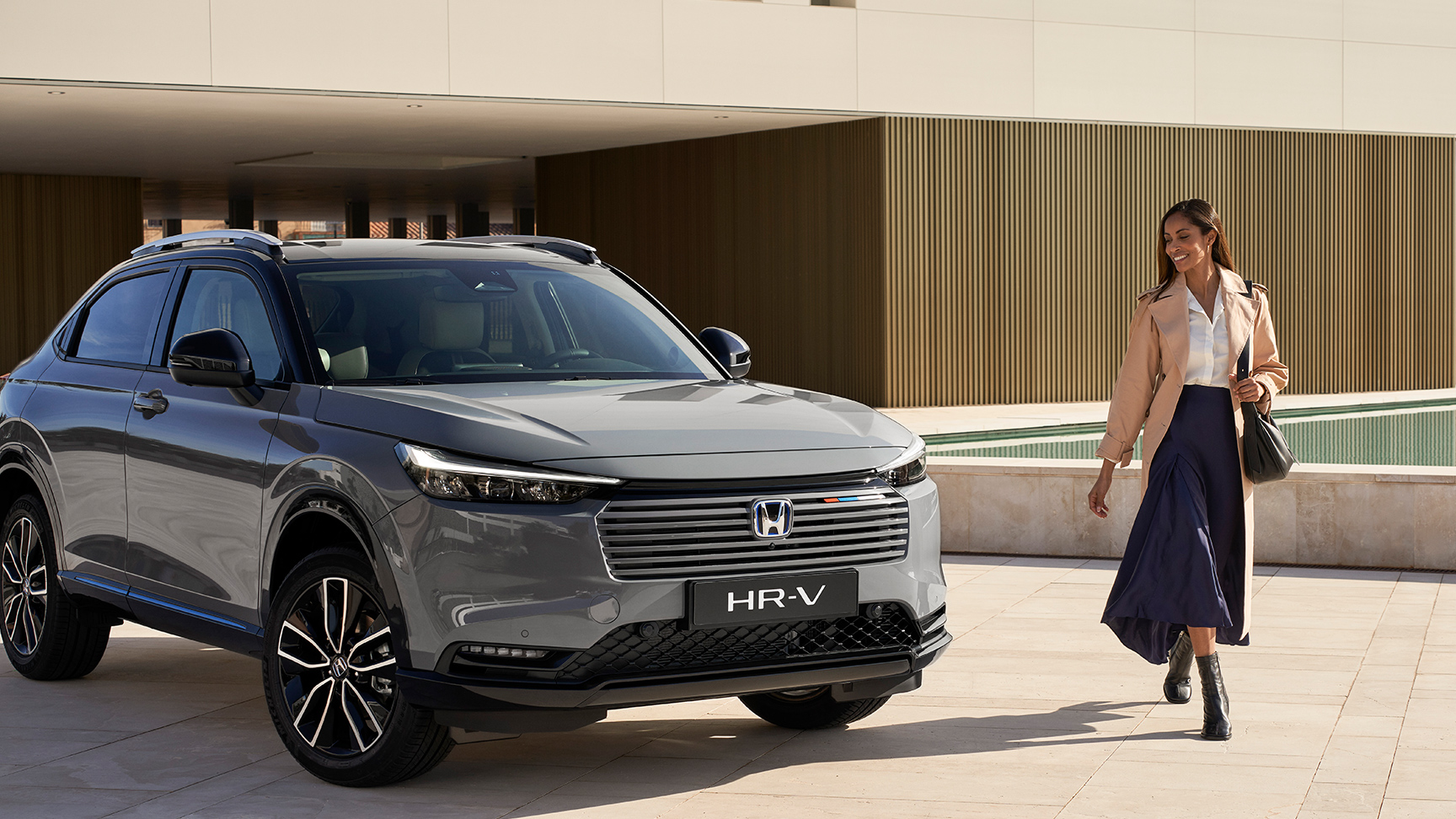 Par går ved siden af ​​HR-V, der er parkeret uden for en bygning. 