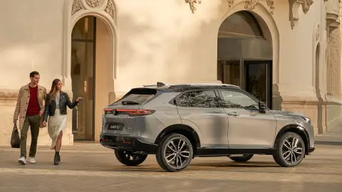 Honda HR-V set fra siden uden for et hotel, hvor et par går forbi. 