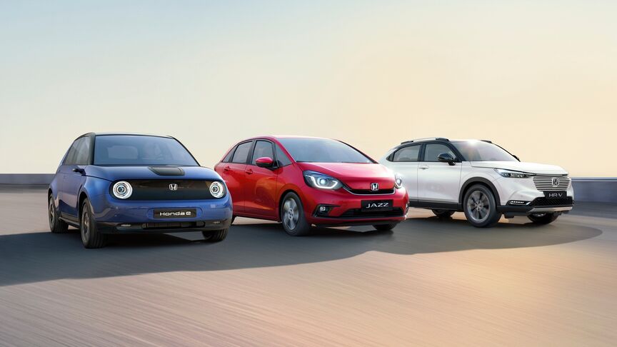 En dame, der står ved siden af White Honda e og bruger My Honda Plus-appen