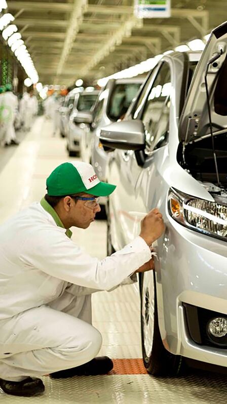 Honda-tekniker, der arbejder på en bil på fabrikken.