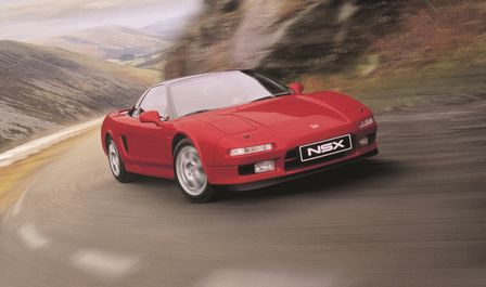 Honda NSX, der kører i et landområde, set skråt forfra.