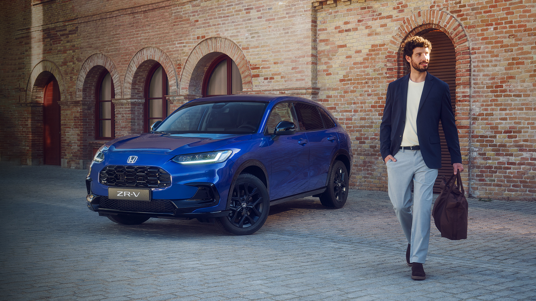 Mand går forbi ZR-V Hybrid suv parkeret i byen.