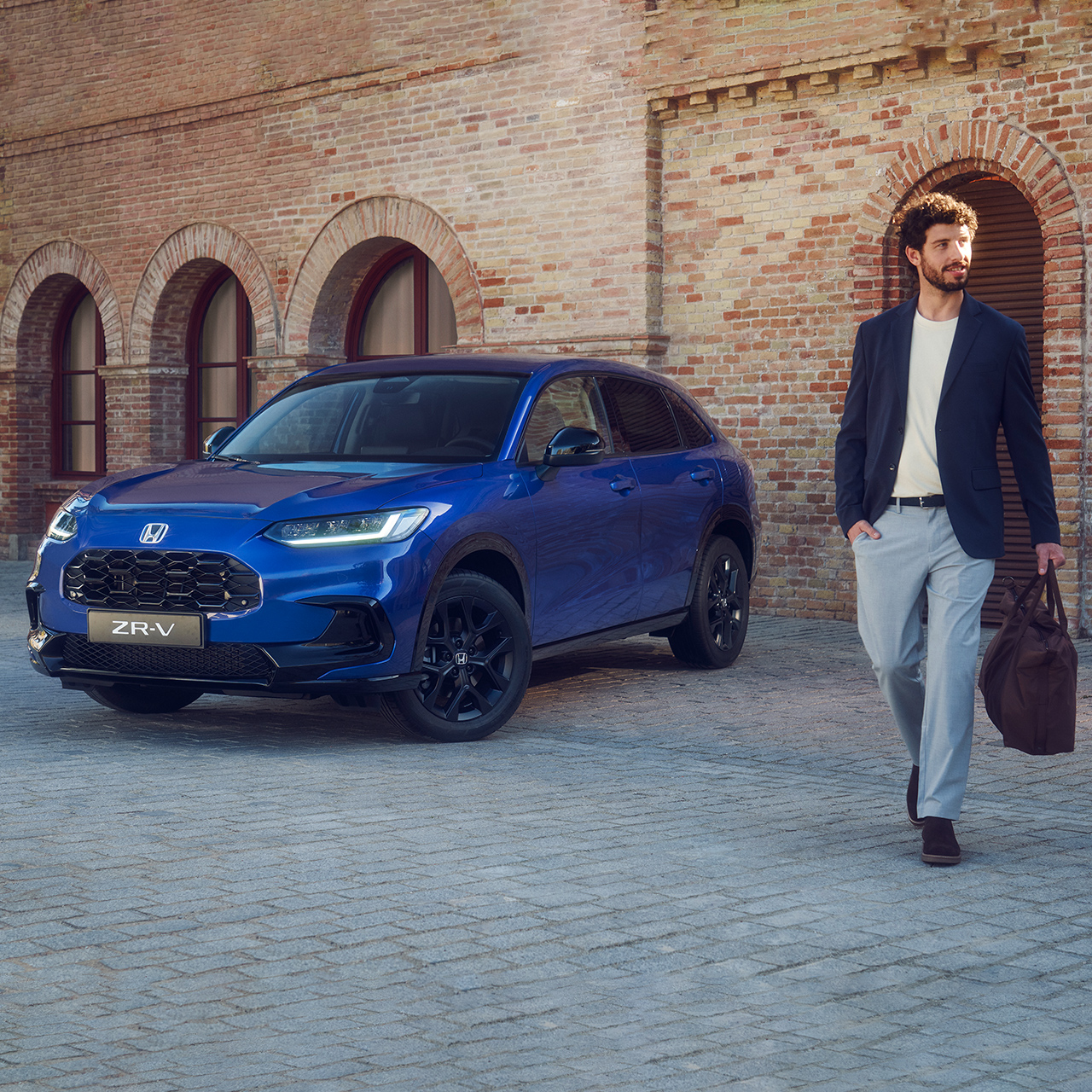 Mand går forbi ZR-V Hybrid suv parkeret i byen.